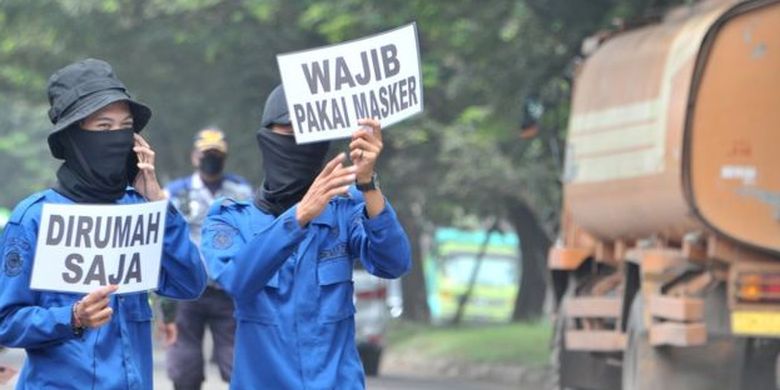 Polisi Pamong Praja Kota Palembang menunjukkan poster kecil bertuliskan anjuran mengenakan masker di check point perbatasan Palembang-Kabupaten Banyuasin Km12 Palembang, Sumatera Selatan, Selasa (28/4. 