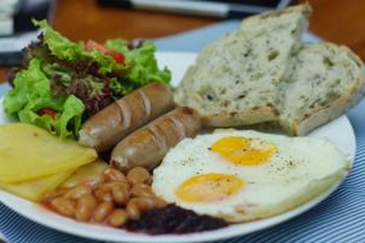 Sajian Big Breakfast di Whale & Co, sebuah kedai kopi mungil di Legian, Bali. Big breakfast terdiri dari dua telur dengan sosis, kacang merah dan disajikan dengan roti dan salad serta sepotong besar Gluten Free Carrot Cake.