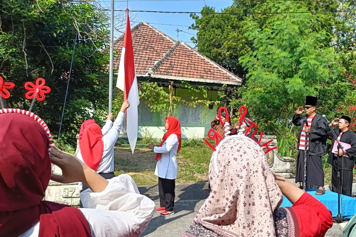 Warga Dusun Brambang, Desa Brambang, Kecamatan Diwek, Kabupaten Jombang, Jawa Timur, mengikuti upacara peringatan HUT ke-80 Kemerdekaan RI yang dilaksanakan di poros jalan perkampungan di wilayah tersebut, Minggu (17/8/2025).