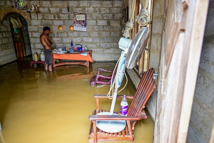 Seorang pria berdiri di dalam rumahnya yang sebagian terendam banjir setelah hujan deras di Kaduwela di pinggiran Colombo, Sri Lanka, pada 28 November 2025. 