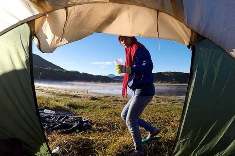 Wisatawan membawa segelas kopi untuk menikmati pagi di tepi Telaga Dringo di Dataran Tinggi Dieng, Kabupaten Banjarnegara, Jawa Tengah.