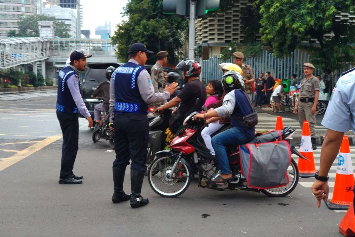 Petugas mencoba memberikan penjelasan pada pengendara yang hendak masuk kawasan car free night Minggu (31/12/2017). Kawasan MH Thamrin dan Sudirman ditutup untuk perayaan tahun baru