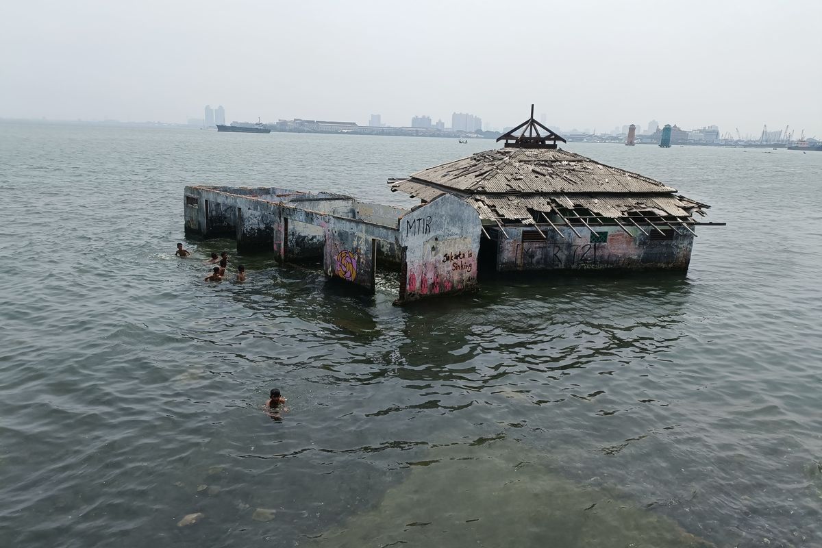 Sekelompok bocah sedang berenang dibalik tembok pembatas antara jalanan dengan laut lepas di kawasan Penjaringan, Jakarta Utara, Minggu (30/1/2022). Tampak didekat mereka ada sebuah Masjid bernama Masjid Wal Adhuna. Diketahui masjid tersebut merupakan saksi bisu mengenai tenggelamnya Ibukota Negara, DKI Jakarta secara perlahan akibat banjir rob. (KOMPAS.com/JOY ANDRE T) 