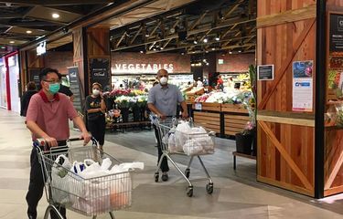 Warga memakai masker mendorong troli belanja meninggalkan Supermarket Cold Storage, Great World City, Singapura Tengah setelah selesai berbelanja, Selasa sore (21/04/2020)