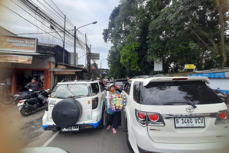 Sejumlah pedagang asongan tampak sibuk menawarkan dagangannya ke pengendara mobil di tengah-tengah kemacetan di Jalur Wisata Puncak Bogor, Jawa Barat, Senin (27/1/2025).