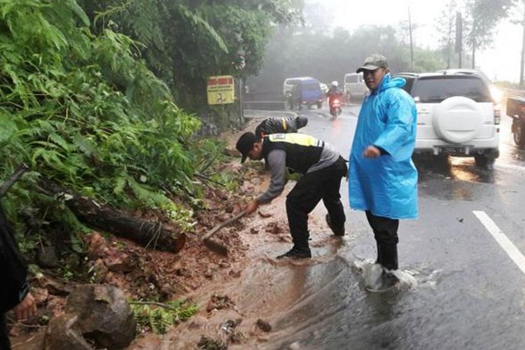 Petugas sedang membersihkan material longsor yang terjadi di Jalan Raya Puncak, Desa Tugu Selatan, Kecamatan Cisarua, Kabupaten Bogor, Minggu (12/2/2017).