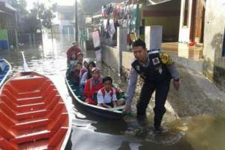 Anggota Polsek Bojongsoang membantu warga dan para siswa melewati genangan air menggunakan perahu di Kampung Cijagra, Kecamatan Bojongsoang, Rabu (21/9/2016). 