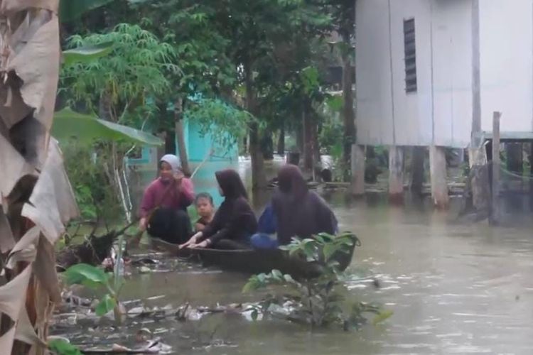 Warga korban banjir menggunakan perahu untuk membeli kebutuhan dapur, di Desa Alam Panjang, Kecamatan Rumbio Jaya, Kabupaten Kampar, Riau, Minggu (31/12/2023).