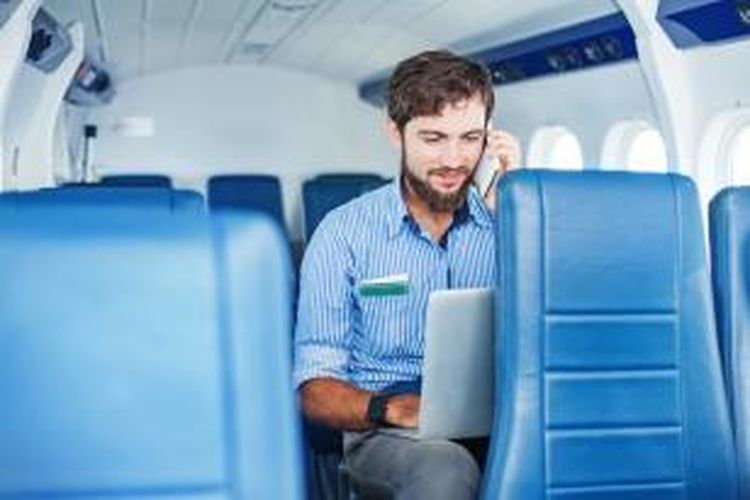 ILUSTRASI - Menggunakan ponsel dan laptop di dalam pesawat.