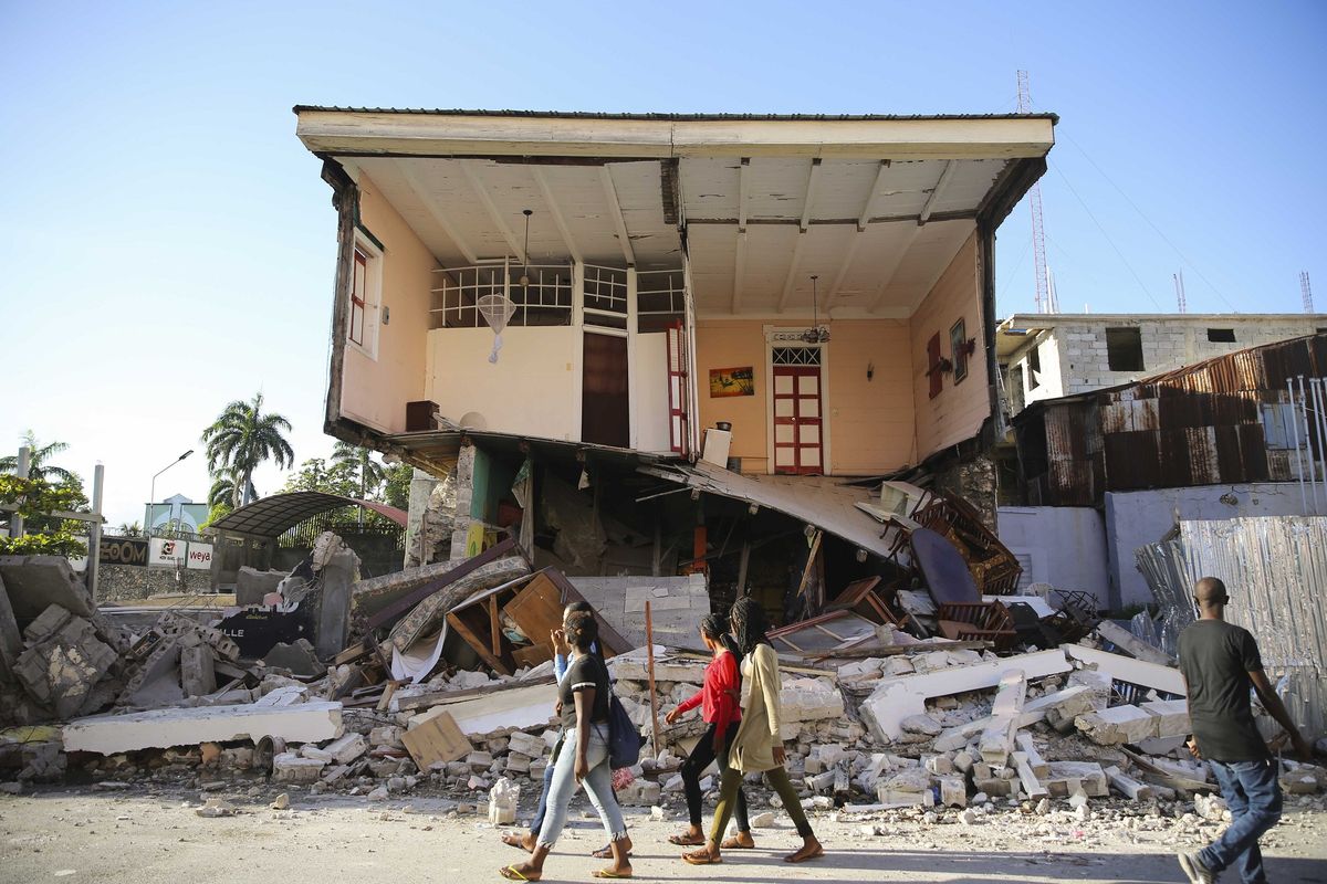 Orang-orang berjalan di depan rumah yang hancur akibat gempa Haiti di Les Cayes, Sabtu (14/8/2021). Gempa bumi berkekuatan M 7,2 ini berpusat di 125 kilometer barat ibu kota Port-au-Prince, menurut keterangan Badan Survei Geologi Amerika Serikat (USGS).