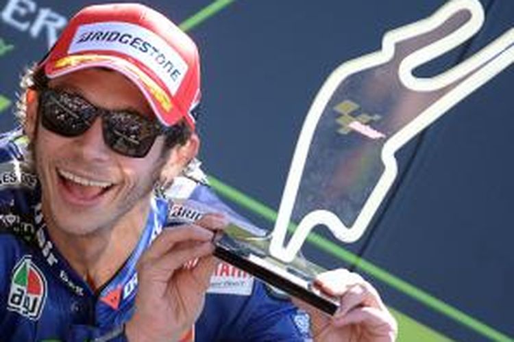 Pebalap Movistar Yamaha asal Italia, Valentino Rossi, memamerkan trofi setelah finis kedua pada GP Perancis di Sirkuit Le Mans, Minggu (17/5/2015).