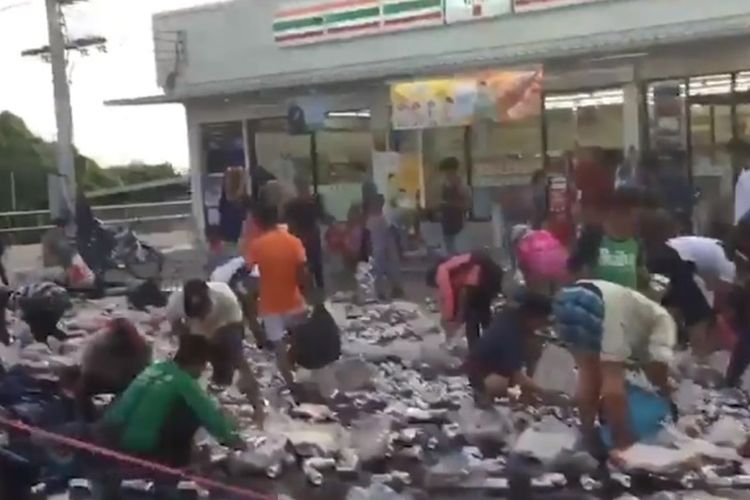 Foto tangkapan layar rekaman video yang memperlihatkan warga di Phuket, Thailand sedang mengumpulkan kaleng bir yang berserakan di jalan setelah truk pengangkutnya terbalik.