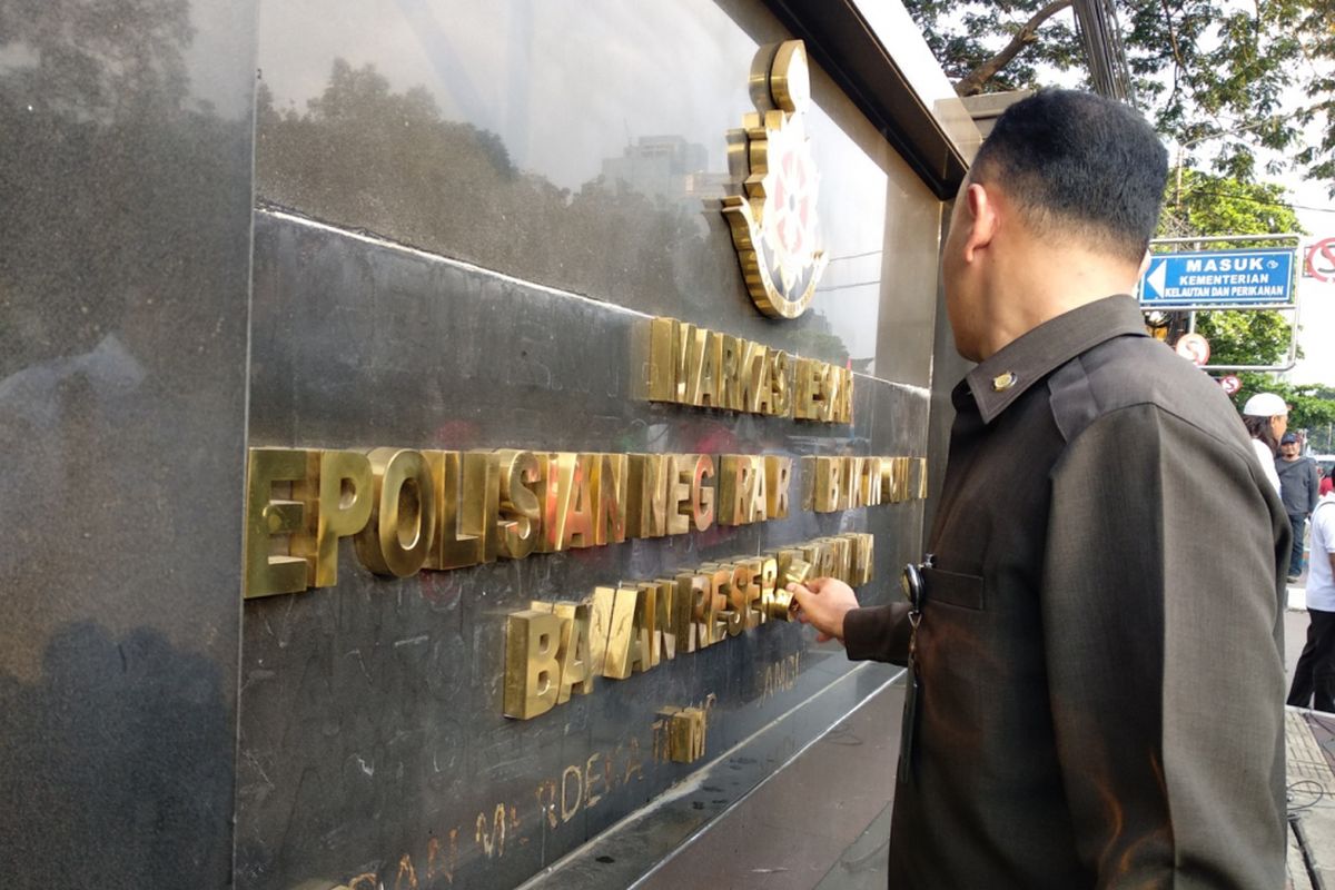 Petugas melihat kerusakan di papan petunjuk kantor Bareskrim Polri, Junat (6/4/2018)