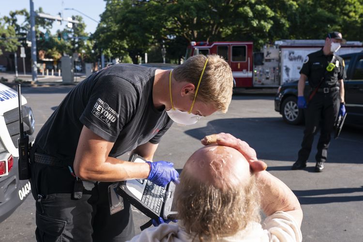 Seorang paramedis dengan ambulans Falck Northwest merawat seorang pria yang mengalami paparan panas selama gelombang panas, Sabtu, 26 Juni 2021.