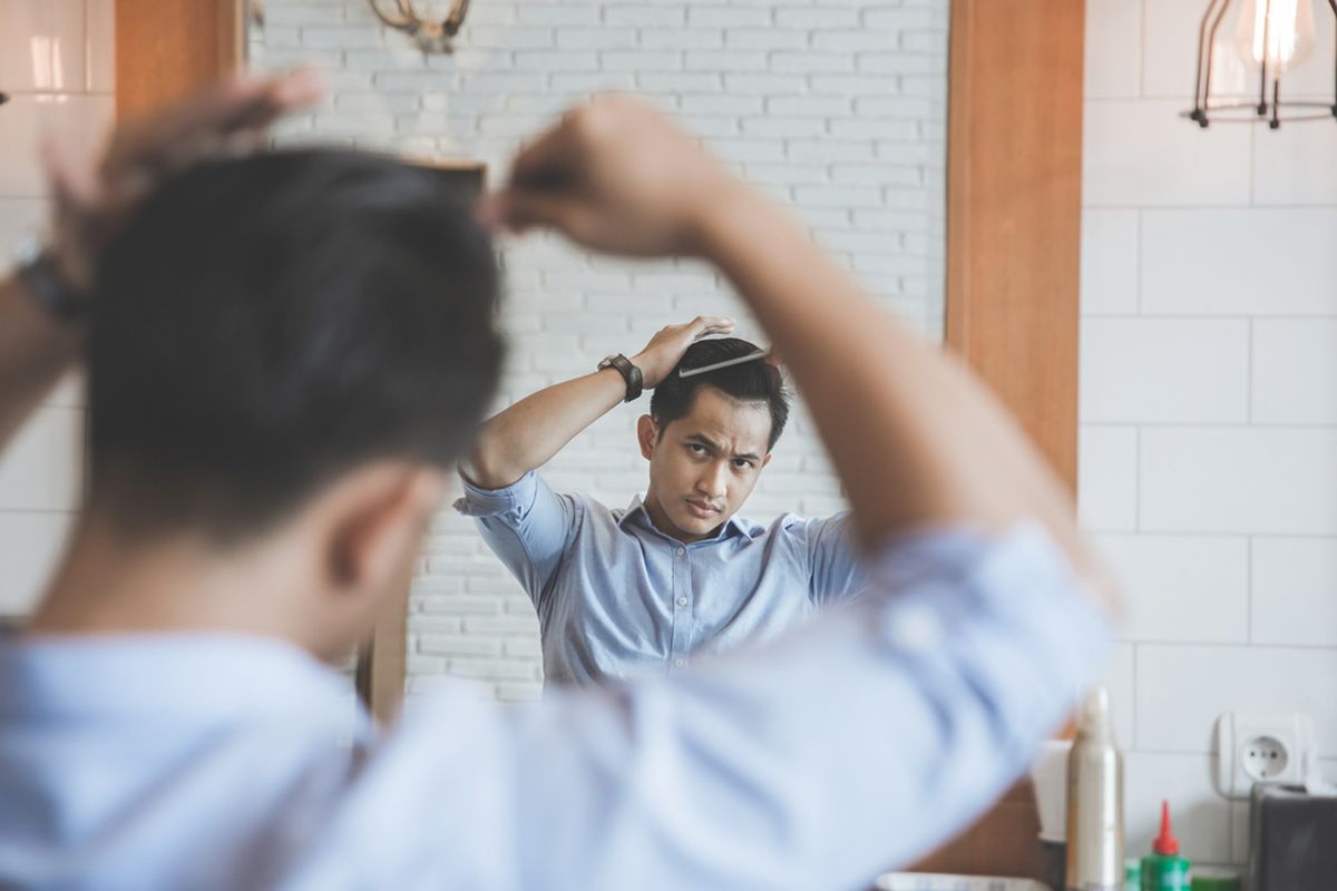 Ilustrasi pria sedang menata rambut dengan pomade.