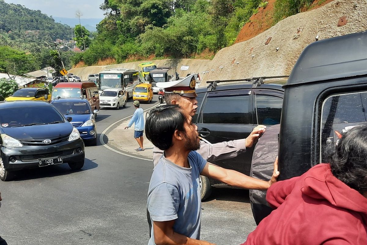 Salah satu mobil pemudik mogok akibat tak kuat menanjak dan mendapatkan bantuan warga serta petugas Kepolisian di Tanjakan Gentong, Kabupaten Tasikmalaya, Jawa Barat, Jumat (6/5/2022).