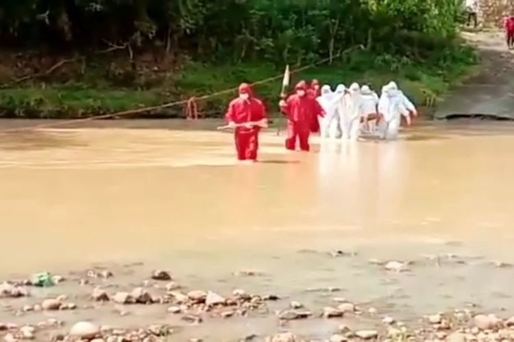 Tim relawan BPBD Kabupaten Wonogiri menyebarangi sungai untuk memakamkan satu jenazah pasien covid-19 di Desa Mojopuro, Kecamatan Jatiroto, Kabupaten Wonogiri, Jawa Tengah, Rabu (23/6/2021).