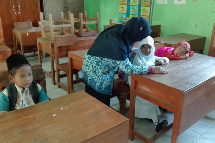 Guru SDN Sukosari, Kelurahan Sukosari, Kecamatan Kartoharjo, Kota Madiun berbincang dengan salah satu siswa baru kelas satu. Meski berada di tengah kota, SDN Sukosari hanya mendapatkan tiga siswa baru. 