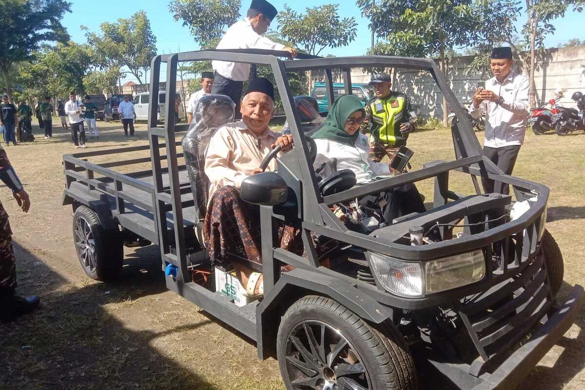 Ketua PCNU Kabupaten Jombang KH. Fahmi Amrullah Hadziq, saat mencoba mengendarai mobil listrik yang dirakit oleh anak-anak SMK NU Unggulan Mojoagung, Kabupaten Jombang, Jawa Timur, Kamis (19/12/2024).
