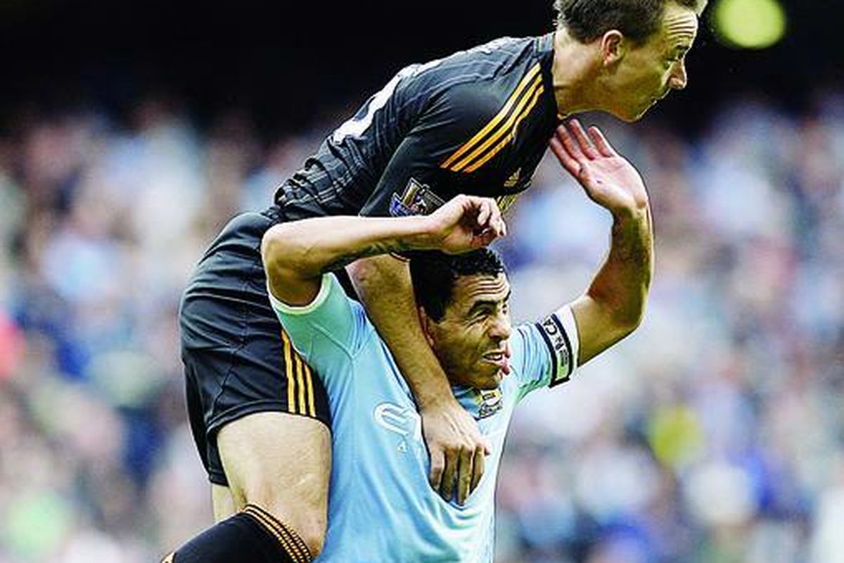 Pemain belakang Chelsea, John Terry (atas), melompat di atas striker Manchester City, Carlos Tevez, untuk menyundul bola pada laga kedua tim di kompetisi Liga Primer di Stadion City of Manchester, Manchester, Inggris, Sabtu (25/9).