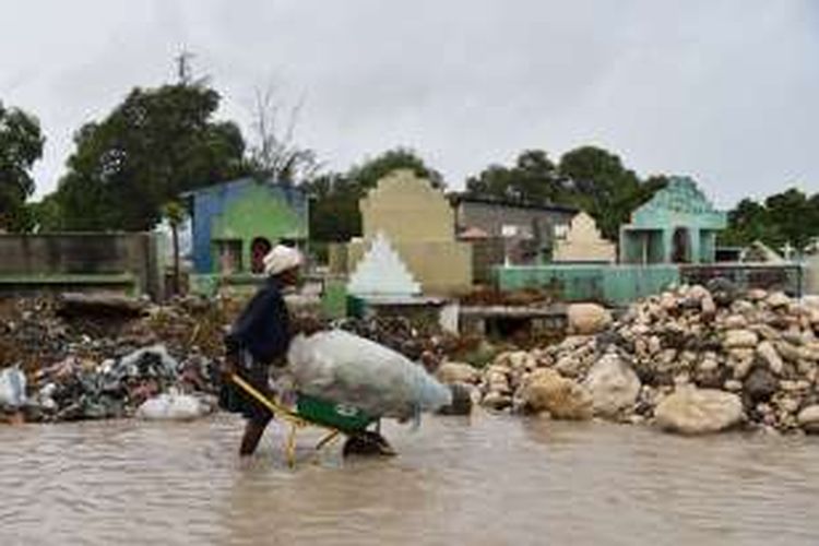 Seorang perempuan mendorong gerobak berisi sedikit harta benda yang selamat dari amiukan badai Matius di ibu kota Port-au-Prince, Haiti.