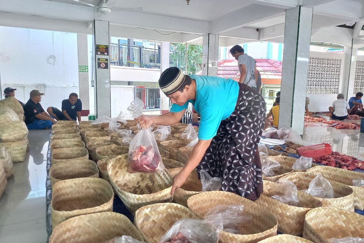 Takmir Masjid Al-Fitrah, Didik Supriyanto, sedang menaruh daging yang telah dipotong ke besek bambu, Kamis (29/6/2023).