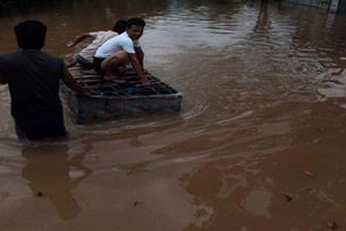 Luapan Kali Pesanggrahan  Warga menggunakan rakit dari tempat tidur bekas saat melintasi banjir di kawasan Sukabumi Selatan, Jakarta Selatan, Selasa (3/4/2012). Banjir tersebut terjadi karena luapan Kali Pesanggrahan setelah hujan deras mengguyur Jakarta dan Bogor sehari sebelumnya.