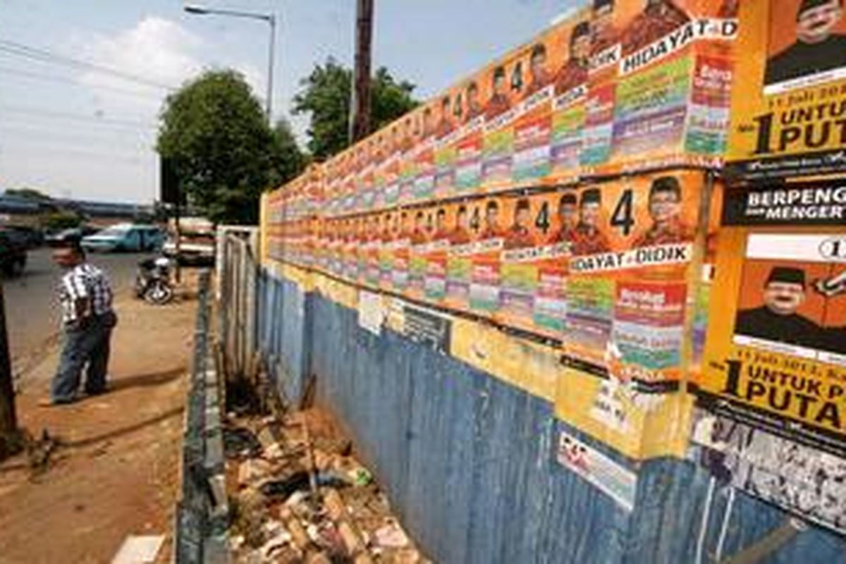 Atribut kampanye pasangan calon gubernur dan wakil gubernur menempel lekat di sejumlah fasilitas umum seperti tiang listrik dan tembok pintu air di kawasan Perempatan Cililitan, Jalan Dewi Sartika, Jakarta, Minggu (8/7/2012). Dalam periode minggu tenang, atribut kampanye sudah harus bersih. 