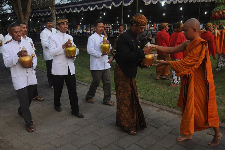 Seorang Biksu menerima kendi air suci dari Umat Buddha saat prosesi Sarana Puja Waisak di Candi Sewu, Prambanan, Klaten, Jawa Tengah, Sabtu (18/5/2019). Kriab Prosesi Sarana Puja Waisak dari Candi Lumbung menuju Candi Sewu dengan membawa api alam Mrapen Grobogan dan air suci dari tujuh sumber mata air itu sebagai wujud penghormatan umat Buddha dalam merayakan Waisak 2563 BE/2019.