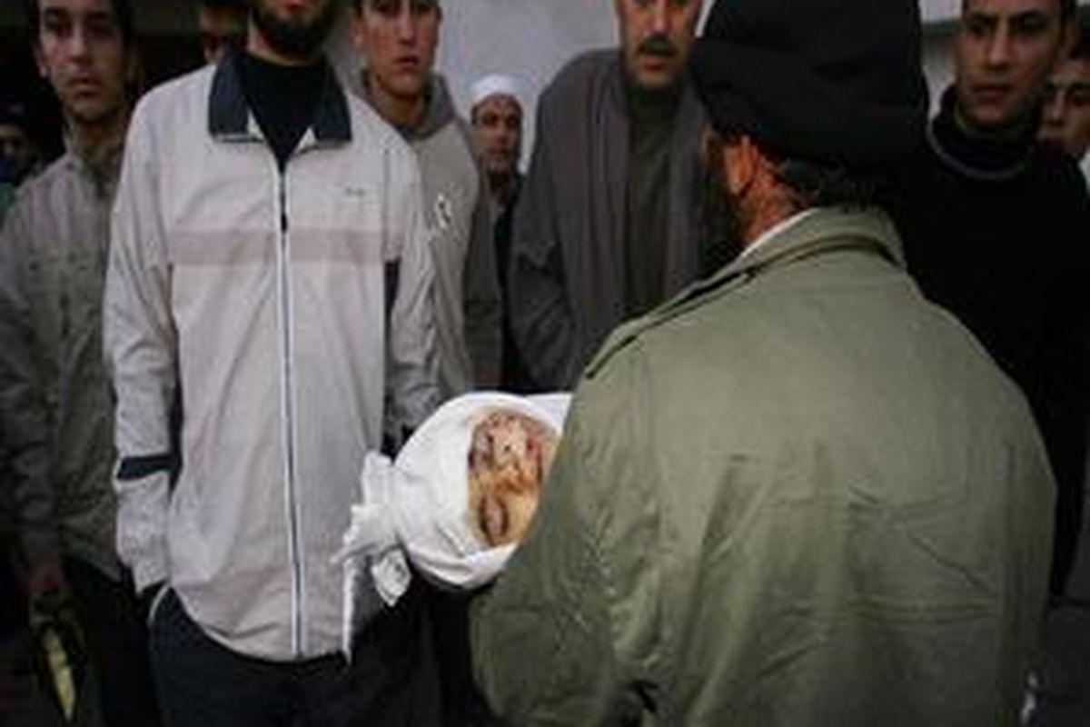 Seorang ayah membopong jenazah putranya berusia setahun yang menjadi korban serangan Israel di Gaza, Senin (5/1). 