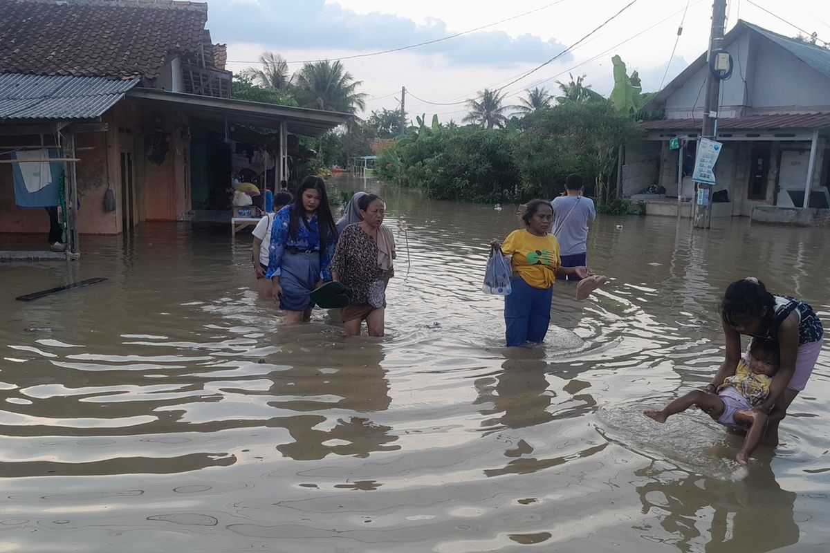 Warga Desa Karangligar, Kecamatan Telukjambe Barat, Karawang, Jawa Barat hendak mengungsi dari terjangan banjir, Kamis (21/11/2024).