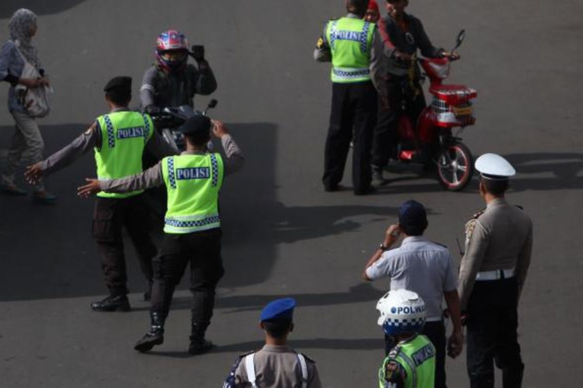 Gabungan petugas kepolisian dan Dinas Perhubungan DKI mengarahkan pengendara sepeda motor yang akan melintas di Jalan MH Thamrin, Jakarta Pusat, Rabu (17/12/2014). Di hari pertama uji coba pembatasan sepeda motor sepanjang Jalan Thamrin-Medan Merdeka Barat, masih terdapat sejumlah pengendara yang belum mengetahui aturan tersebut. KOMPAS/LUCKY PRANSISKA 