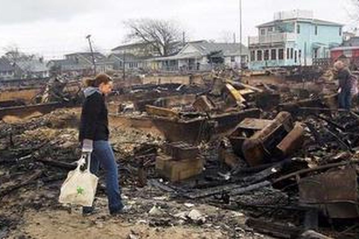 Seorang warga Queens, New York City, melihat-lihat puing-puing rumahnya pascaterjangan Badai Sandy, Selasa (30/10/2012). Badai Sandy yang membawa angin berkekuatan setara topan dan hujan deras telah menghancurkan sebagian wilayah Pantai Timur AS.  