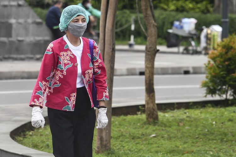 Pekerja mengenakan pelindung diri saat melintasi kawasan Sudirman, Jakarta, Rabu (6/1/2021). Pemerintah kembali memberlakukan pengetatan pembatasan pergerakan dengan menerapkan aturan Work From Office (WFO) maksimal hanya 25 persen dari kapasitas kantor dan berlaku di Pulau Jawa dan Bali. ANTARA FOTO/Muhammad Adimaja/rwa.
