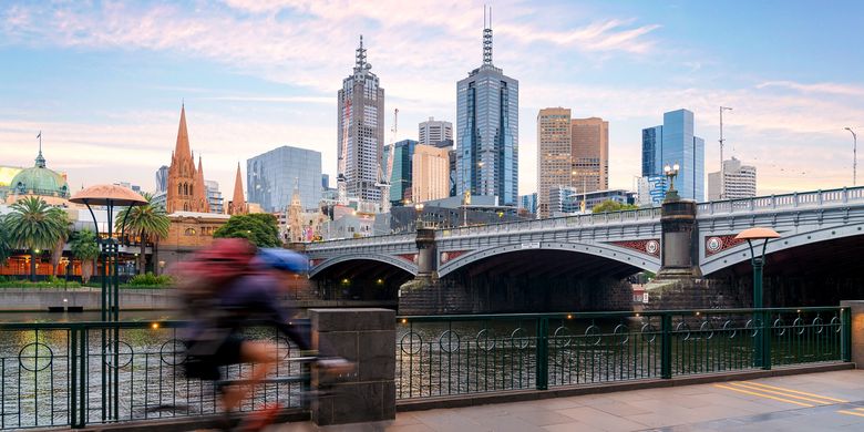 Orang Australia bersepeda untuk olahraga di sekitar Sungai Yarra dengan pemandangan kota Melbpourne City Financial District dengan pencakar langit pada pagi hari di Melbourne, Victoria, Australia.