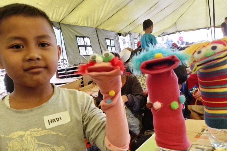 Seorang anak korban gempa Cianjur, Jawa Barat, memerlihatkan boneka tangan yang baru saja dibuatnya usai mengikuti kegiatan pendampingan psikososial yang diinisiasi KG Media.