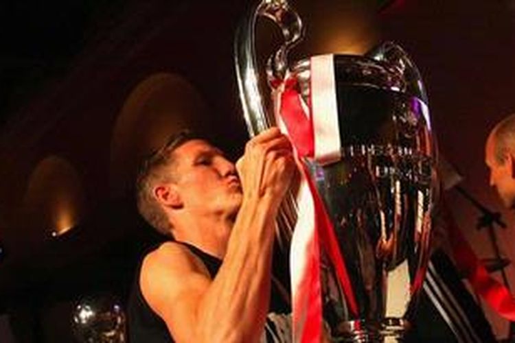 Gelandang Bayern Muenchen, Bastian Schweinsteiger, mengangkat trofi Liga Champions yang diraih timnya.