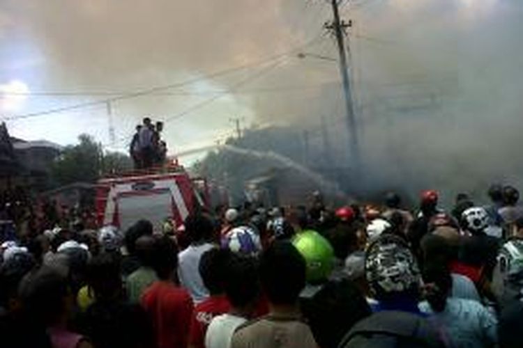 Ratusan warga berkerumun ditengah mobil pemadam kebakaran yang berupaya memadamkan api yang meludeskan dua buah rumah warga di Kabupaten Sinjai, Sulawesi Selatan. Senin, (09/09/2013).