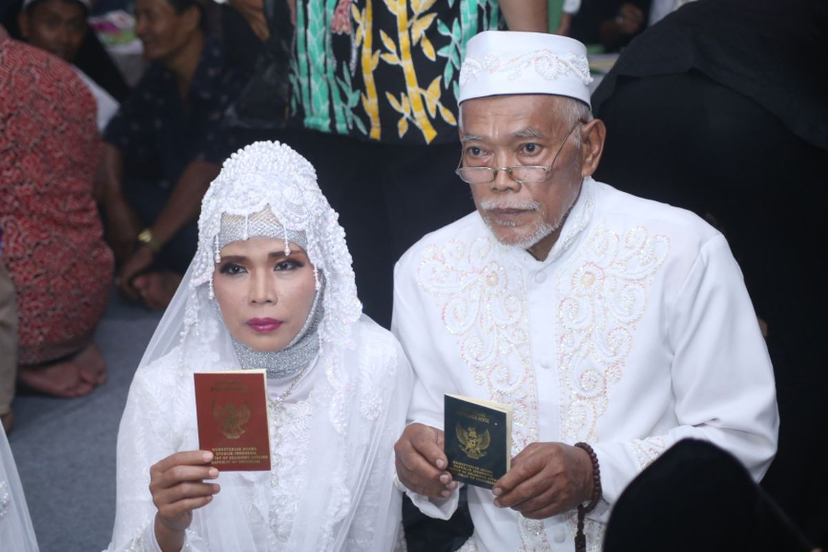 Sepasang pengantin menunjukkan buku nikahnya usai mengikuti nikah massal di jalan MH Thamrin, Jakarta Pusat, Minggu (31/12/2017). Nikah massal yang diadakan oleh pemerintah DKI Jakarta ini diikuti sebanyak 437 pasangan pengantin dari berbagai usia.
