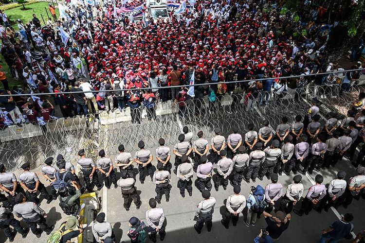 Massa melakukan aksi dengan penjagaan aparat keamanan saat peringatan Hari Buruh Internasional 2019 di Jakarta, Rabu (1/5/2019). Aksi yang diperingati tahunan setiap tanggal 1 Mei itu digelar serentak di seluruh dunia untuk menyuarakan kesejahteraan bagi buruh.