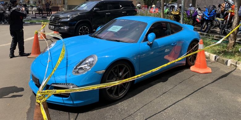 Mobil jenis Porsche 911 Carrera S berwarna biru milik tersangka Doni Salmanan yang disita polisi bakal menjadi barang bukti terkait kasus penipuan dan pencucian uang investasi ilegan binary option sang selebgram sudah digaris polisi di Bareskrim Polri, Senin (14/3/2022).