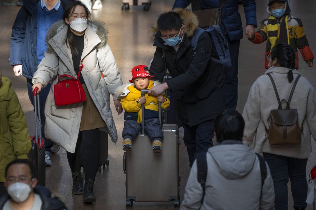 Pasangan membawa seorang anak di atas koper di Stasiun Kereta Api Beijing Barat di Beijing, Rabu, 18 Januari 2023. Populasi China yang perlahan menyusut akan menimbulkan tantangan baru bagi para pemimpin China. Berbagai kebijakan dikeluarkan untuk menggenjot kelahiran.