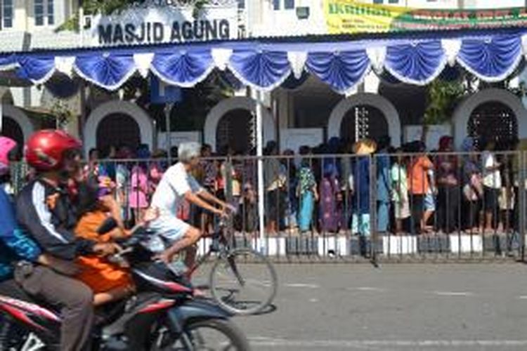 Warga melintas di Antrian kupon daging kurban di halaman Masjid Agung Kota Tegal, Jawa Tengah, Sabtu (4/10/2014). Banyak diantara mereka yang membawa serta anak balitanya.      