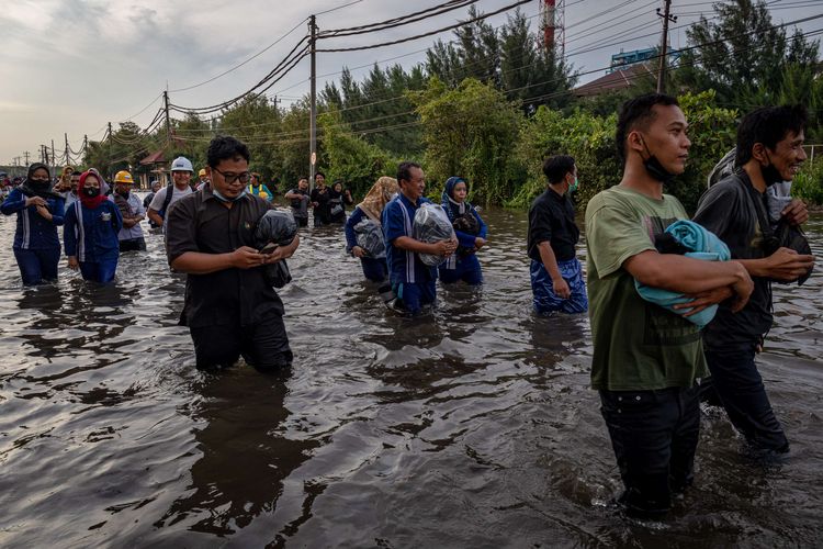 Sejumlah warga yang didominasi pekerja industri kawasan pelabuhan berjalan menembus banjir limpasan air laut ke daratan atau rob yang merendam kawasan Pelabuhan Tanjung Emas Semarang, Jawa Tengah, Senin (23/5/2022). Banjir rob dengan ketinggian bervariasi hingga mencapai 1,5 meter itu disebabkan oleh tingginya pasang air laut serta adanya tanggul yang jebol di kawasan tersebut. Sementara itu personel dari Basarnas, TNI-Polri dan relawan diterjunkan untuk membantu evakuasi para pekerja maupun warga.