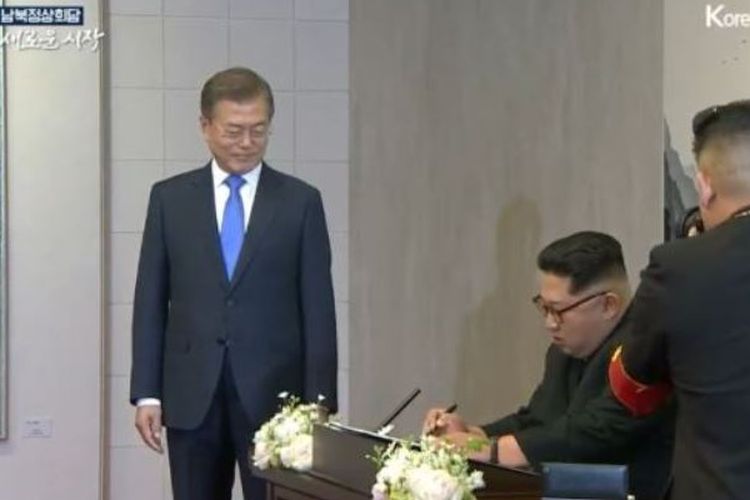 Inilah momen di mana Pemimpin Korea Utara Kim Jong Un menuliskan pesan di buku tamu disaksikan Presiden Korea Selatan Moon Jae In dalam Konferensi Tingkat Tinggi Antar-Korea di Panmunjom, Jumat (27/4/2018).