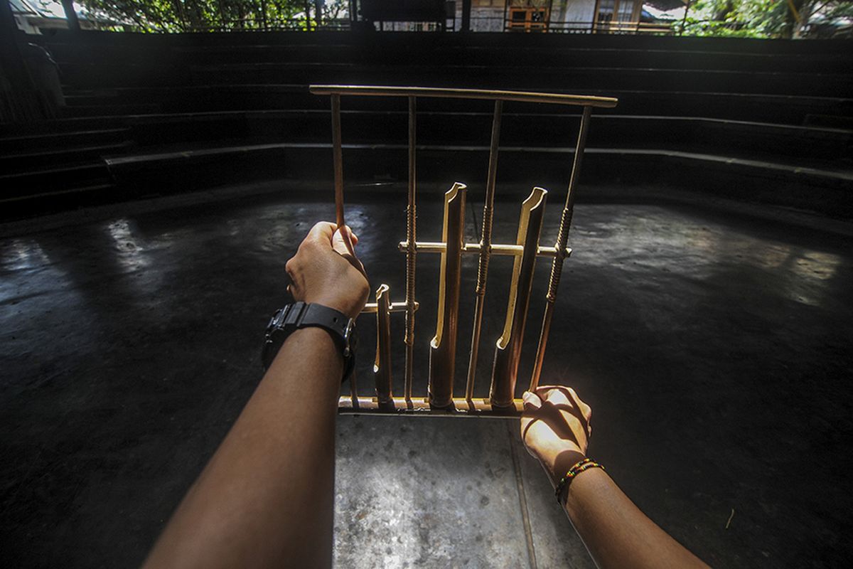 Seorang instruktur memegang angklung di aula pementasan yang kosong di Saung Angklung Udjo, Bandung, Jawa Barat, Minggu (24/1/2021). Pandemi membuat aktivitas bisnis pariwisata di Saung Angklung Udjo cukup terpuruk dengan hanya dikunjungi tak lebih dari 20 orang dalam sepekan, padahal saat kondisi normal mampu menarik hingga dua ribu orang per hari.