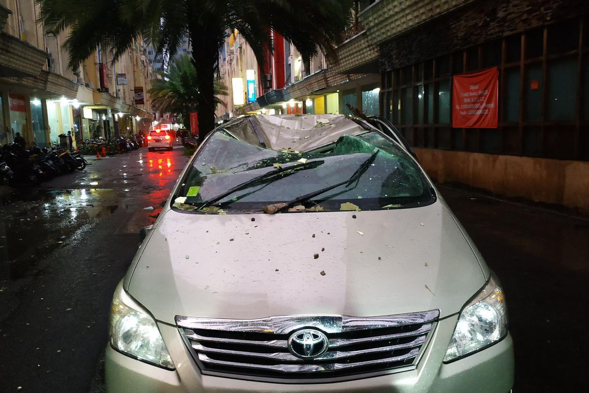 Mobil ringsek di area pertokoan Saladdin akibat tertimpa panel bangunan ketika hujan deras dan angin kencang melanda kota Depok pada Selasa (21/9/2021) sore.