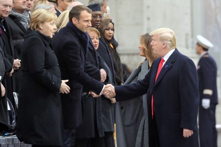 Presiden AS Donald Trump berjabat tangan dengan Presiden Prancis Emmanuel Macron dan Kanselir Jerman Angela Merkel, tiba bersama istrinya, Ibu Negara Pertama AS Melania Trump untuk menghadiri upacara di Arc de Triomphe di Paris, Minggu (11/11/2018). (AFP/Ludovic Marin)
