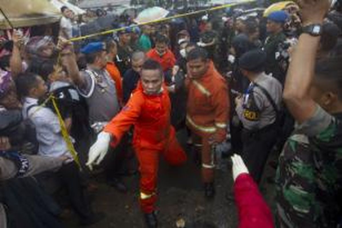 Petugas berusaha mengevakuasi korban di lokasi tabrakan kereta rel listrik (KRL) jurusan Serpong-Tanah Abang dengan truk tangki pengangkut bahan bakar di pelintasan Pondok Betung, Bintaro, Jakarta Selatan, Senin (9/12/2013). Kecelakaan mengakibatkan sejumlah rangkaian gerbong dan truk tangki terbakar, menyebabkan 10 orang tewas dan puluhan orang luka-luka.