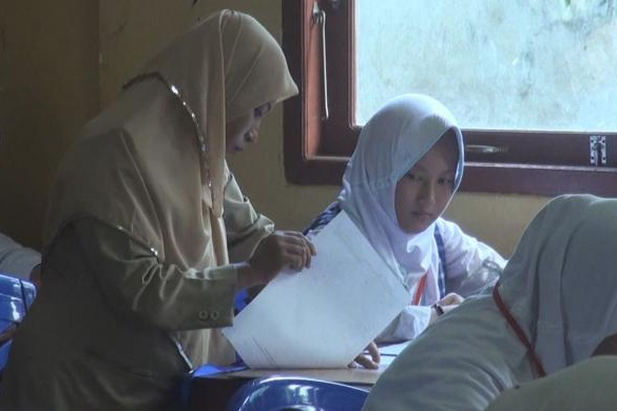 Seorang guru pengawas temgah menjelaskan soal kepada siswa yang ikut ujian